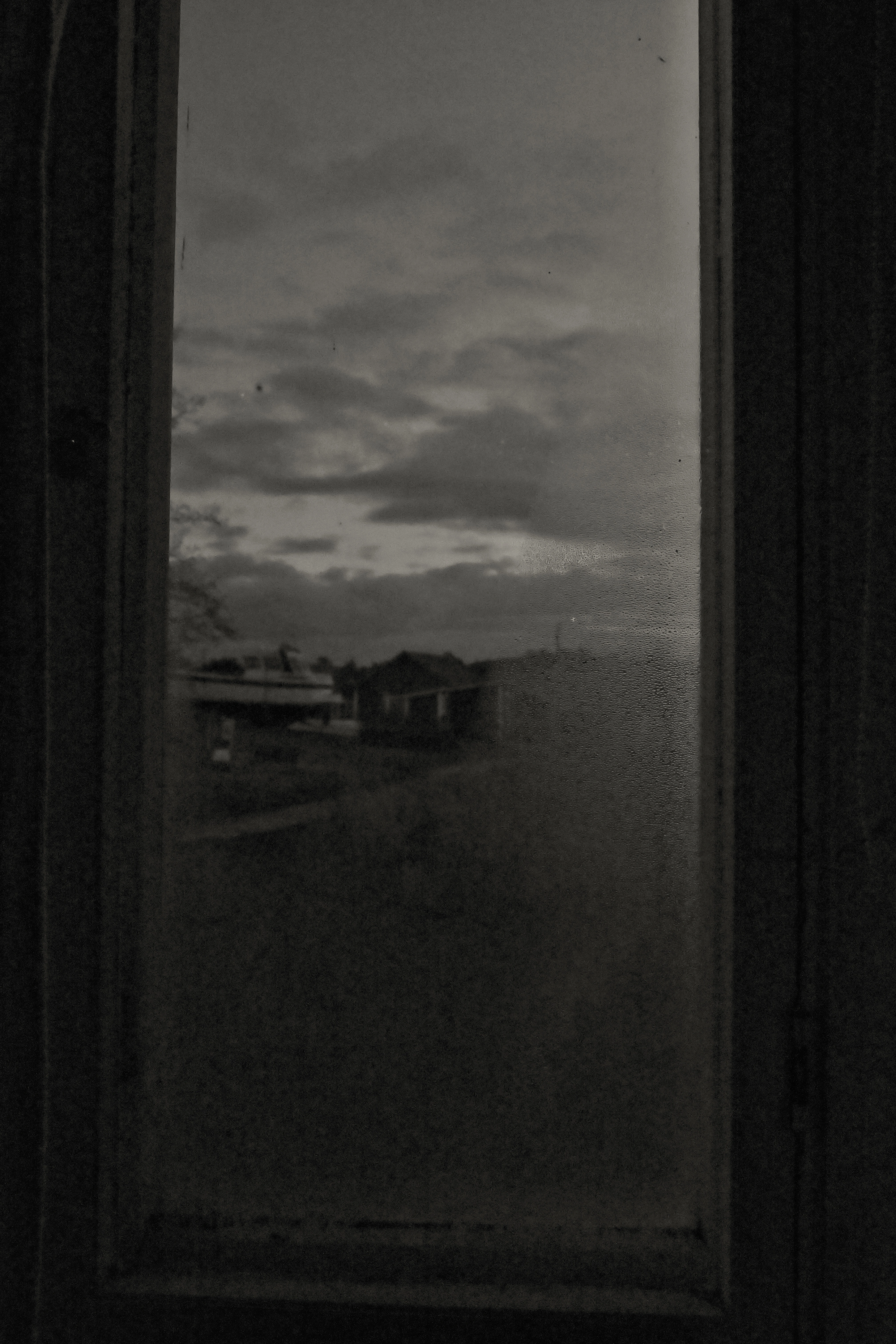 Black and white photo of a fogged up window with a village in the background